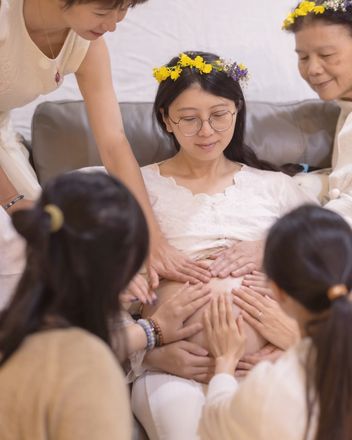 女人們把手一起放在孕婦的肚子上
