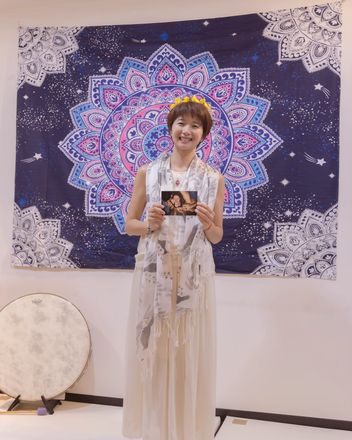 頭戴花環的女人站在曼陀羅掛布前
